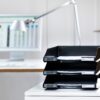 Drei übereinander gestapelte KLASSIK Briefablagen in schwarz, in einem modernen, hellen Büro
